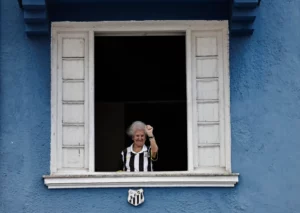 A Santos fan waves to mourners queuing to pay their respects to Brazilian soccer legend Pele near Vila Belmiro stadium. [Ueslei Marcelino/Reuters]