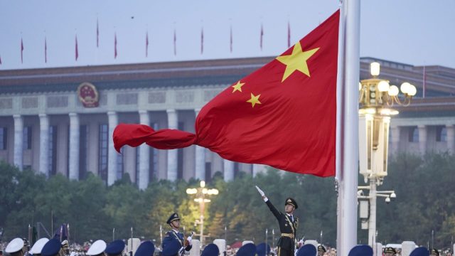 FILE – In this photo released by Xinhua News Agency, a member of the Chinese honor guard unfurls the Chinese national flag during a flag raising ceremony to mark the 73rd anniversary of the founding of the People’s Republic of China held at the Tiananmen Square in Beijing on Oct. 1, 2022. (Chen Zhonghao/Xinhua via AP, File)
