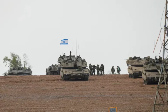 Israeli soldiers are seen in a staging ground near the Israeli-Gaza border in southern Israel [Ohad Zwigenberg/AP Photo]