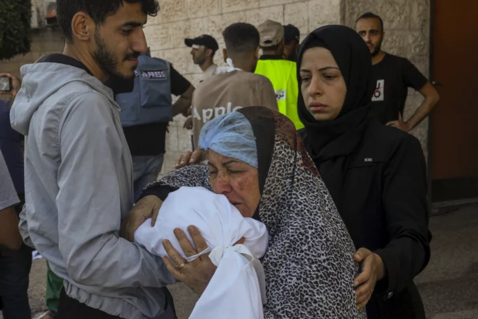 Palestinian children look at the building of the Zanon family, destroyed in Israeli airstrikes in Rafah, Gaza Strip, Saturday, Oct. 14, 2023. (AP Photo/Hatem Ali)