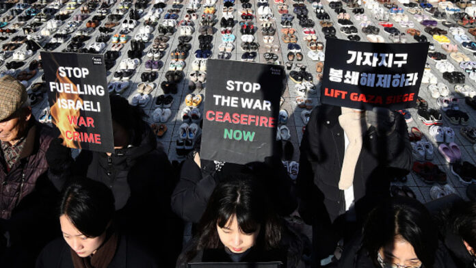 Activists hold placards in front of pairs of shoes symbolizing Palestinian victims during a rally for Gaza on November 17 [Getty]