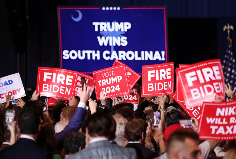 Trump supporters hold signs as they attend his primary night party in Columbia, South Carolina, on February 24 [Alyssa Pointer/Reuters]