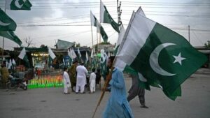 A man carrying Pakistan's national flags, walks through a street on the eve of country's Independence Day celebrations in Peshawar on August 13.(AFP