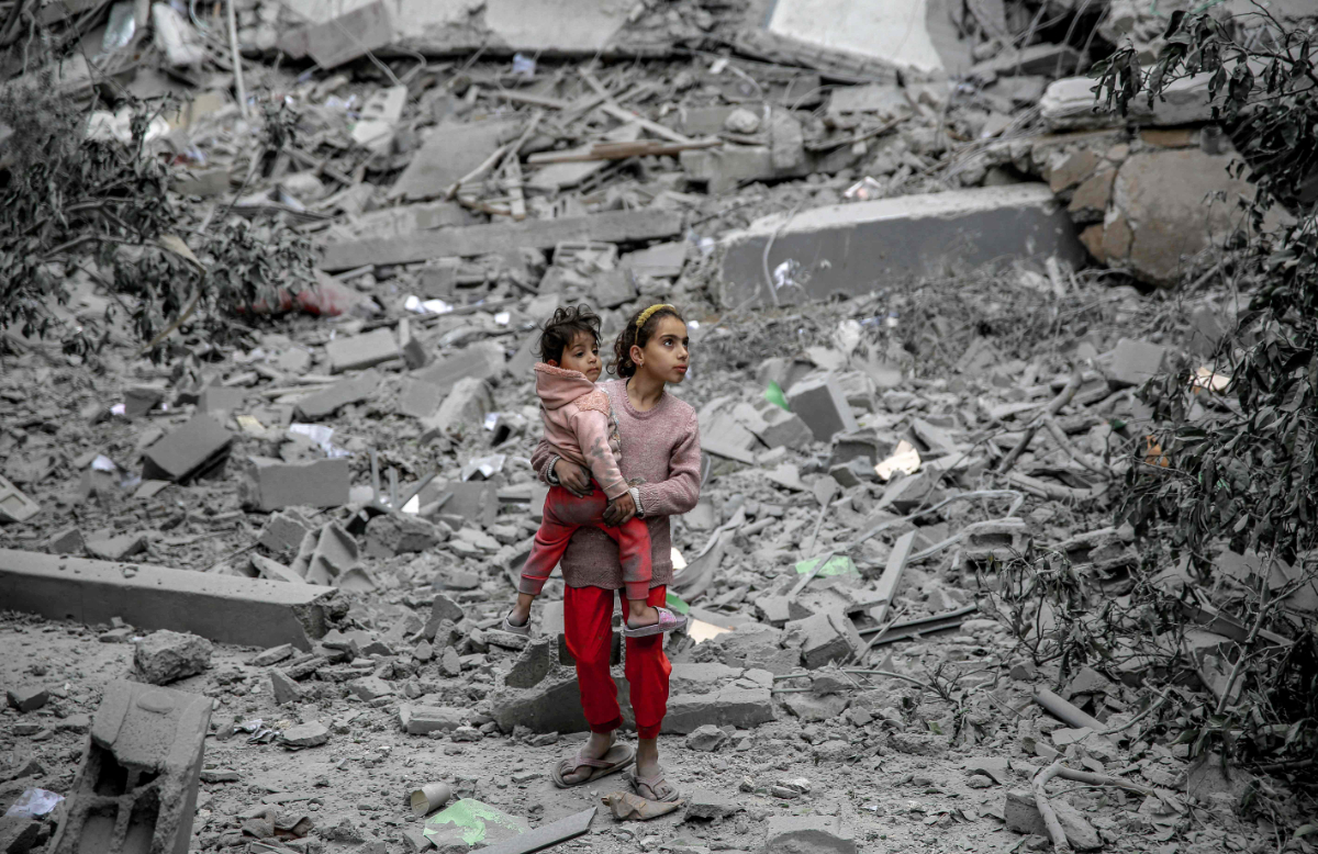 A  Palestinian girl carries a child through the rubble of houses destroyed by Israeli bombardment in Gaza City on March 3, 2024, amid the ongoing conflict between Israel and the Hamas movement. (AFP)