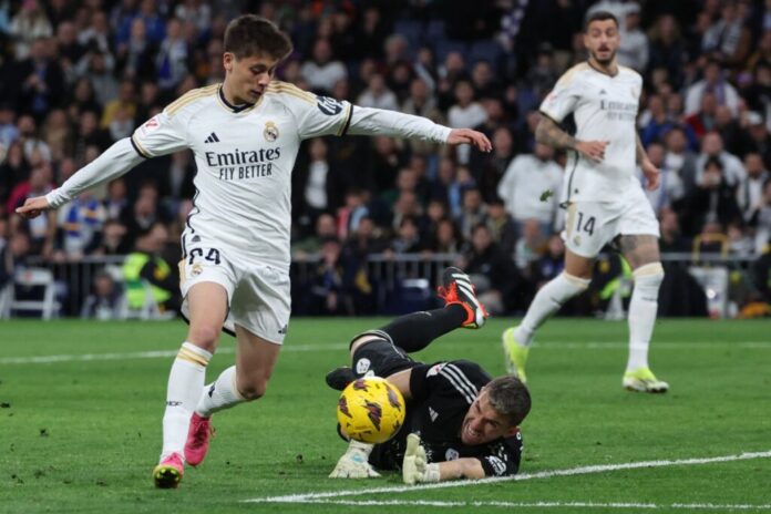 Real Madrid’s Turkish midfielder #24 Arda Guler (L) scores his team’s fourth goal during the Spanish league football match between Real Madrid CF and RC Celta de Vigo at the Santiago Bernabeu stadium in Madrid on March 10, 2024. (Photo by Pierre-Philippe MARCOU / AFP)