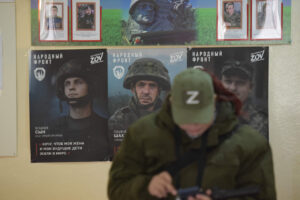 A woman is seen in front of posters and photographs of servicemen at a polling station during Russia's presidential election in Donetsk, Russian-controlled Ukraine, on March 16, 2024. (AFP)