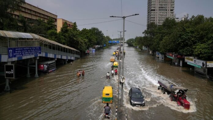 Commuters drive through a street inundated with floodwaters from the swollen river Yamuna, in New Delhi, India, Friday, July 14, 2023. Manish Swarup/AP