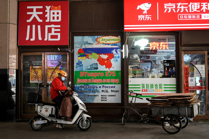 A delivery man stands in front of a billboard advertising international logistics transportation to Russia, outside a convenience store in Ritan International Trade Center in Beijing. (AFP)