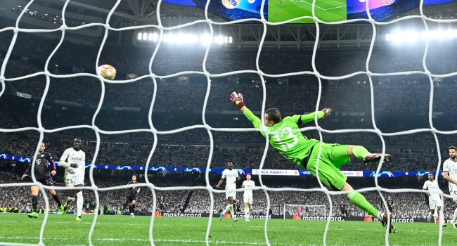 Bayern Munich’s Canadian midfielder #19 Alphonso Davies scores his team’s first goal in spite of Real Madrid’s Ukrainian goalkeeper #13 Andriy Lunin during the UEFA Champions League semi final second leg football match between Real Madrid CF and FC Bayern Munich at the Santiago Bernabeu stadium in Madrid on May 8, 2024. (Photo by OSCAR DEL POZO / AFP)