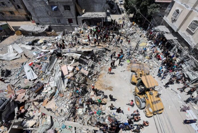 Palestinians gather as rescuers search for casualties trapped under the rubble of of a house hit in an Israeli strike, amid the ongoing conflict between Israel and the Palestinian Islamist group Hamas, in Nuseirat refugee camp in the central Gaza Strip, May 14, 2024. REUTERS/Ramadan Abed