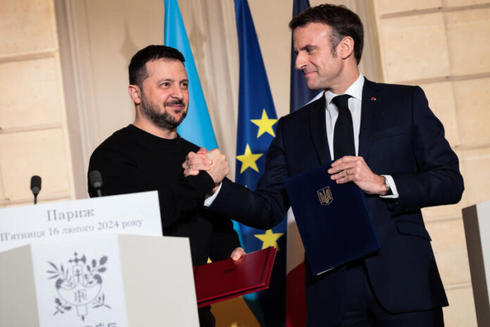 Emmanuel Macron and Volodymyr Zelensky shaking hands after signing the bilateral agreement between France and Ukraine, in Paris, on February 16, 2024. CYRIL BITTON / DIVERGENCE FOR LE MONDE