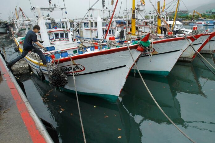 FILE - A fisherman leaps to his boat docked in harbor in Toucheng, north eastern Taiwan, Aug. 21, 2013. Taiwan said the Chinese coast guard boarded a Taiwanese fishing boat Tuesday, July 2, 2024, before steering it to a port in mainland China, and demanded that Beijing release the vessel. (AP Photo/Wally Santana, File)