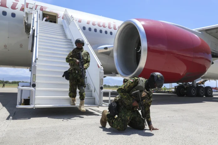 A Kenyan police officer who is part of a UN-backed multinational force kneels on the tarmac in thanks after landing at Toussaint Louverture International Airport in Port-au-Prince, Haiti, Tuesday, July 16, 2024. Another 200 police officers from Kenya arrived for a U.N.-backed mission led by the East African country to battle violent gangs that have taken over parts of the Caribbean country. (AP Photo/Odelyn Joseph)