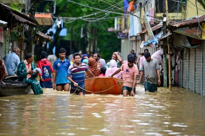 People wade through floodwaters in Feni, among the worst-hit areas in Bangladesh, on August 23 [Munir Uz Zaman/AFP]