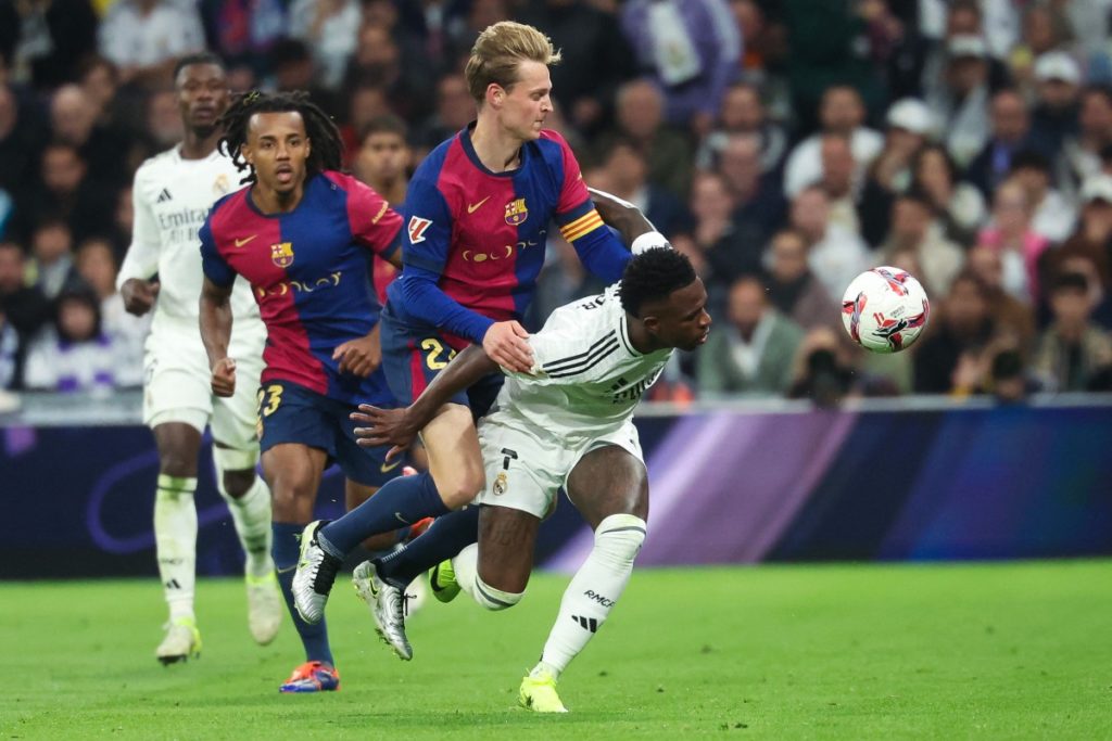 Vinicius Junior (R) is challenged by Frenkie De Jong during the Spanish league football match between Real Madrid CF and FC Barcelona at the Santiago Bernabeu stadium in Madrid on October 26, 2024. (Photo by Pierre-Philippe MARCOU / AFP)