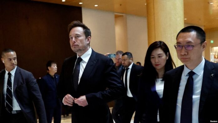 FILE—Tesla Chief Executive Officer Elon Musk, center, walks next to Tesla's Senior Vice President Tom Zhu and Vice President Grace Tao as he leaves a hotel in Beijing, May 31, 2023.