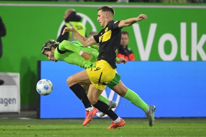 Dortmund’s Nico Schlotterbeck, right, and Wolfsburg’s Jonas Wind fight for the ball during the Bundesliga soccer match between VfL Wolfsburg and Borussia Dortmund, in Wolfsburg, Germany, Sunday Dec. 22, 2024. (Swen Pförtner/dpa via AP)