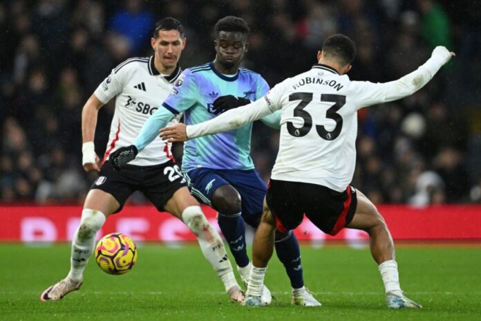Fulham’s English-born US defender #33 Antonee Robinson (R) vies with Arsenal’s English midfielder #07 Bukayo Saka (C) during the English Premier League football match between Fulham and Arsenal at Craven Cottage in London on December 8, 2024. (Photo by JUSTIN TALLIS / AFP)  Fulham’s English-born US defender #33 Antonee Robinson (R) vies with Arsenal’s English midfielder #07 Bukayo Saka (C) during the English Premier League football match between Fulham and Arsenal at Craven Cottage in London on December 8, 2024. (Photo by JUSTIN TALLIS / AFP)