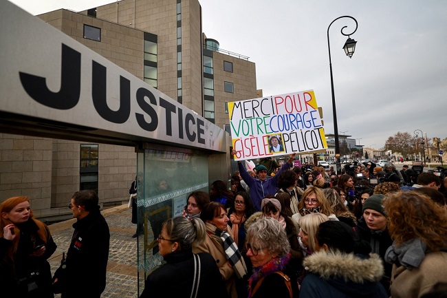French artist and activist Voltuan holds up a placard reading in French “Thank you for your courage Gisele Pelicot” as people gather outside the courthouse in Avignon on December 19, 2024, waiting for the verdict in the trial of a man, with 50 others, accused of drugging his wife and orchestrating multiple rapes over nearly a decade. (Photo by Clement MAHOUDEAU / AFP)