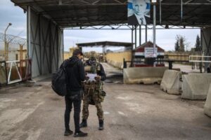 A view of a gate to Khmeimim Air Base on Dec. 29, 2024. The Russian soldier, at right, is said to be inspecting a petition from a Syrian man from Aleppo who was a former resident of Russia, asking to repatriate his daughter back to Syria. AAREF WATAD/AFP via Getty Images AAREF WATAD