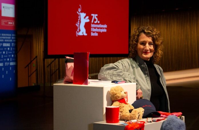 Berlinale director Tricia Tuttle poses with merchandising products for the upcoming International Film Festival Berlinale before the Berlinale press conference in Berlin on January 21, 2025. (Photo by Vincent Kolbe / AFP)