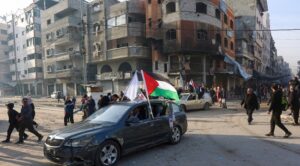 People ride in a car adroned with a Palestinian flag along a street in Gaza City on January 19, 2025, following the ceasefire deal in the Israel-Hamas war. (Photo by Omar AL-QATTAA / AFP)