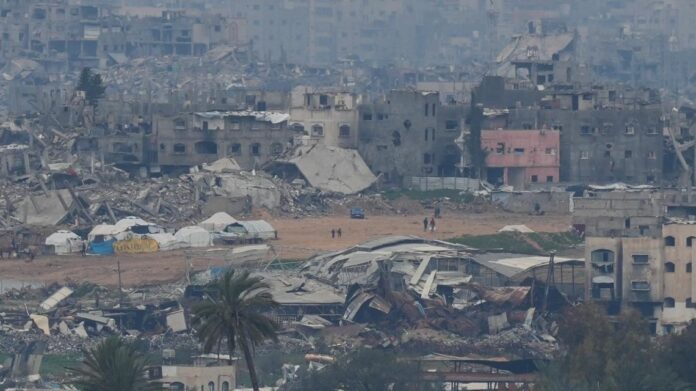 Palestinians are seen near destroyed buildings by Israeli bombardments inside the northern Gaza Strip as seen from southern Israel, Feb. 9, 2025. Credit: (Photo/Ohad Zwigenberg)