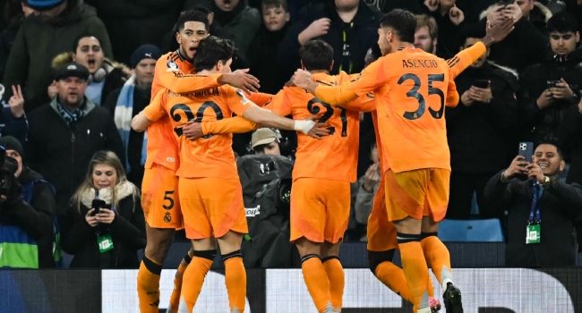 Real Madrid’s English midfielder #05 Jude Bellingham (L) celebrates with teammates after scoring his team’s third goal during the UEFA Champions League football match between Manchester City and Real Madrid at the Etihad Stadium in Manchester, north west England, on February 11, 2025. (Photo by Paul ELLIS / AFP)