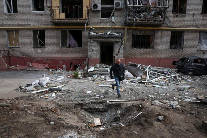 A person runs out of an apartment block to avoid falling debris from a building hit during a Russian drone strike in a residential area, amid Russia’s attack on Ukraine, in Dnipro, Ukraine March 29, 2025. | Photo Credit: REUTERS