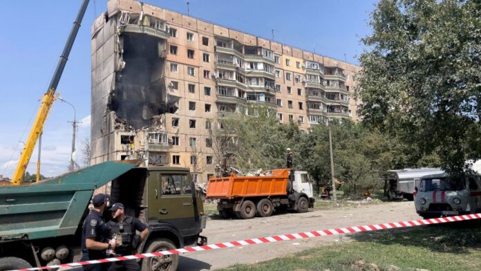 Police officers stand guard near a residential building partially destroyed as a result of a Russian missile strike in Kryvyi Rih on July 31, 2023.