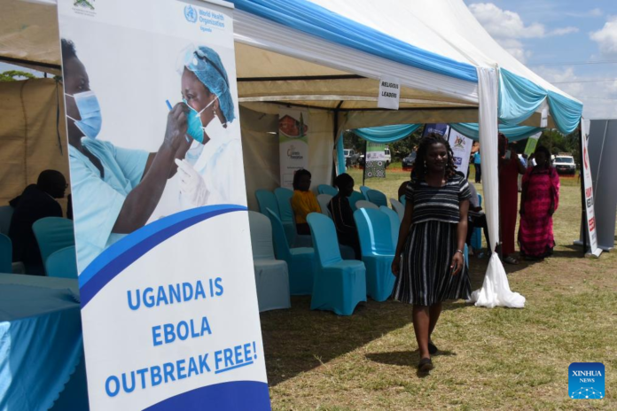 A woman walks past a sign during a ceremony declaring an end to the Ebola Sudan Virus Disease (SVD) outbreak in Mbale, Uganda, April 26, 2025. Uganda on Saturday declared an end to the Ebola Sudan Virus Disease (SVD) outbreak after completing a 42-day mandatory countdown without any new confirmed cases reported, less than three months after the virus was detected in the capital, Kampala. (Photo by Patrick Onen/ Xinhua)