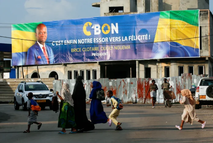 People cross the street near a banner showing Brice Clotaire Oligui Nguema, presidential candidate and Gabonese junta leader, ahead of the 2025 Gabonese presidential election in Libreville, Gabon April 7, 2025. REUTERS/Luc Gnago/File Photo 