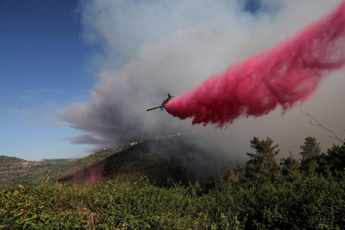 A firefighting plane releases retardant over fires raging in Jerusalem hills, Sunday. Credit: Ronen Zvulun / Reuters