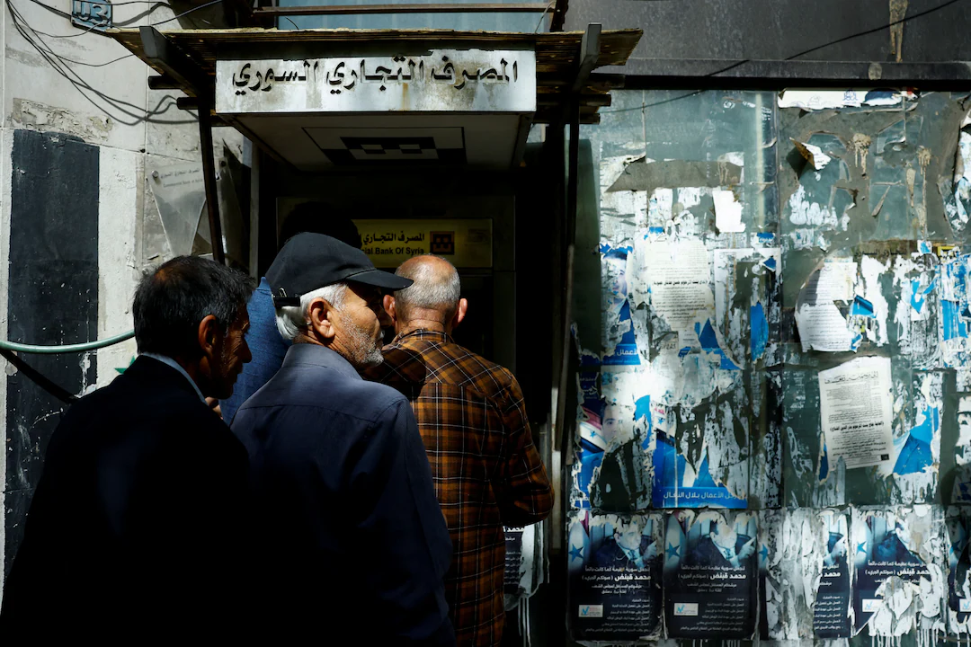 People gather at an ATM machine of Commercial Bank of Syria, after U.S. President Donald Trump announced that he would order the lifting of sanctions on Syria, in Damascus, Syria May 14, 2025. REUTERS/Yamam al ShaarĀ Purchase LicensingĀ Rights, opens new tab