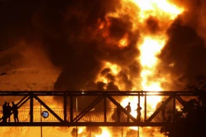 People watch from a bridge as flames from an Israeli attack rise from Sharan Oil depot, following Israeli strikes on Iran, in Tehran, Iran, June 15, 2025. Majid Asgaripour/WANA (West Asia News Agency) via REUTERS