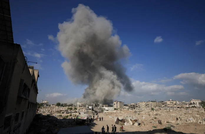 Palestinians gather near a cemetery as smoke rises following an explosion during an Israeli operation in Gaza City, August 28, 2025. REUTERS/Dawoud Abu Alkas/File Photo 