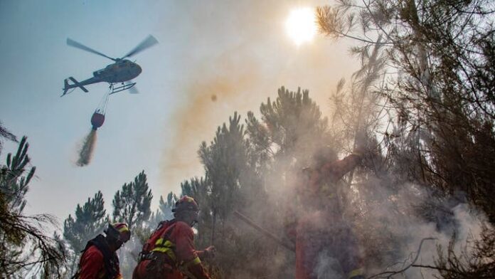 This handout photo released by the Military Emergency Unit (UME) on July 31, 2025, shows a firefighter helicopter dropping water as firefighters on the ground battle a wildfire near Caminomorisco, in the western Spanish province of Caceres. (AFP)