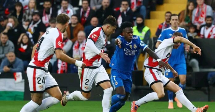 1/5]Soccer Football - LaLiga - Rayo Vallecano v Real Madrid - Campo de Futbol de Vallecas, Madrid, Spain - November 9, 2025 Real Madrid's Vinicius Junior in action with Rayo Vallecano's Andrei Ratiu, Florian Lejeune and Jorge de Frutos REUTERS/Susana Vera