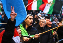 Iran Executes Teenage Wrestling Champ, Two Others Amid Protest Crackdown Anti-Iranian regime protesters wave Iranian flags before the 1979 revolution with the Lion and Sun emblems during a gathering outside the Iranian Embassy, central London, on January 9, 2026. Photo by HENRY NICHOLLS / AFP