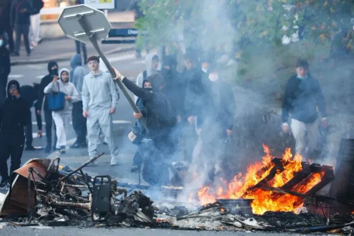 A protestor throws a stop sign into a fire as protesting students carry out blockading action near the Kerichen high school in Brest, western France, on October 2, 2026. Photo by FRED TANNEAU / AFP